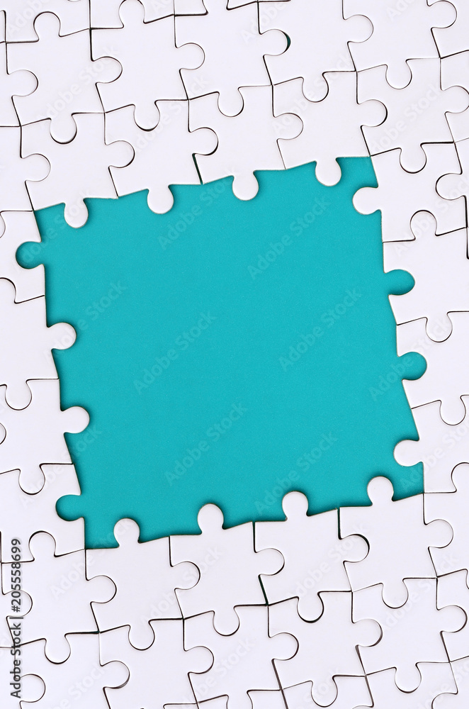 Wall mural framing in the form of a rectangle, made of a white jigsaw puzzle around the blue space