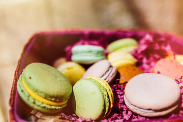 Colorful macaroons and flowers on wooden table. Sweet macarons i
