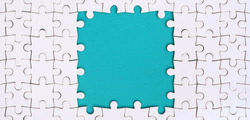 Framing in the form of a rectangle, made of a white jigsaw puzzle around the blue space - obrazy, fototapety, plakaty