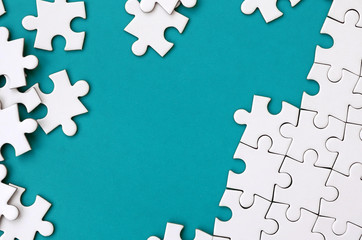 Fragment of a folded white jigsaw puzzle and a pile of uncombed puzzle elements against the...