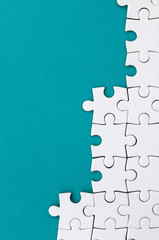 Fragment of a folded white jigsaw puzzle on the background of a blue plastic surface. Texture photo...