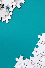 Fragment of a folded white jigsaw puzzle and a pile of uncombed puzzle elements against the...