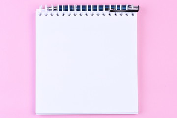 Top view of blank note paper book with pen on pink background