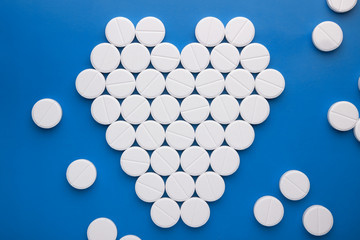 heart of white pills on a brightly blue background