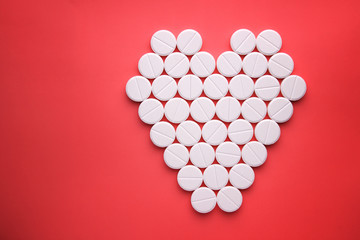 heart of white pills on a brightly red background, copy space