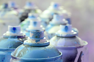 A lot of dirty and used aerosol cans of bright blue paint. Macro photograph with shallow depth of...