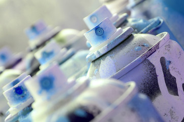 A lot of dirty and used aerosol cans of bright blue paint. Macro photograph with shallow depth of...