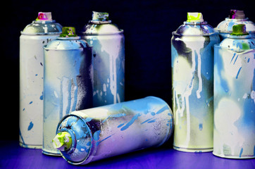 Still life with a large number of used colorful spray cans of aerosol paint lying on the treated...