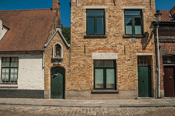 Brick facade of old houses and doors with blue sky, in an empty street of Bruges. With many canals and old buildings, this graceful town is a World Heritage Site of Unesco. Northwestern Belgium.