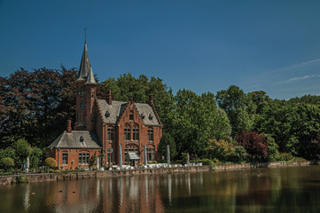 Amazing lake surrounded by greenery and old brick building on the other side in Bruges. With many canals and old buildings, this graceful town is a World Heritage Site of Unesco. Northwestern Belgium.