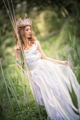 Fairy-tale princess in the crown in a magical forest.