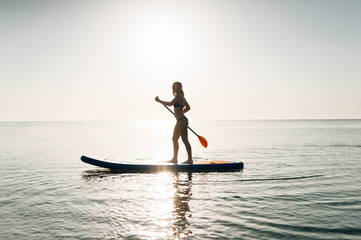 Stand up paddle board woman paddleboarding on Hawaii standing happy on paddleboard on blue water.