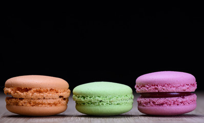 Pink, green and orange macaroons on wooden table