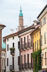 Fototapeta premium Bottom perspective of the famous Clock Tower of Vicenza seen from one of the town streets with some old palaces in the foreground