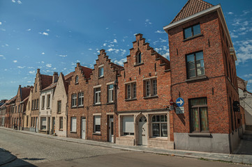 Brick facade of old houses with a blue sunny sky in an empty street of Bruges. With many canals and old buildings, this graceful town is a World Heritage Site of Unesco. Northwestern Belgium.