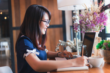 Asian young business woman working make a note of something making notes on in coffee shop like the background.