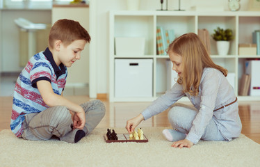 Naklejka premium Two little children playing chess at home