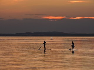 Paddleboarding women on a lake in sunset, Germany