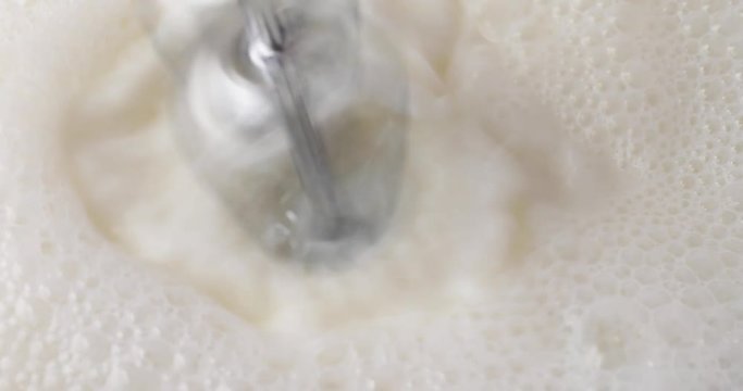 Close video of using electric beaters to froth milk.