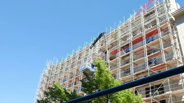 Arrow of the working crane over the building under construction.The working woods close repaired or the building under construction.