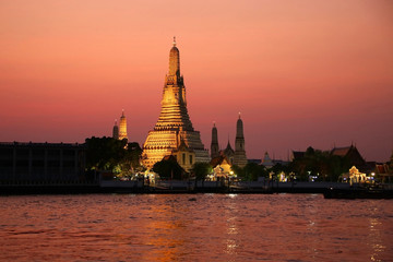 Naklejka premium The temple of Dawn or Wat Arun on the bank of the Chao Phrya river at sunset, Bangkok, Thailand.