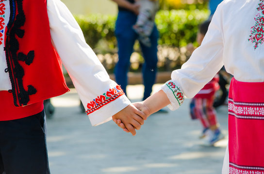 Bulgarian girl and a boy in ethnical red costumes holding hands