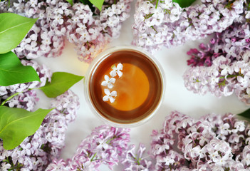 cup of hot tea with lilak background and some little flowers