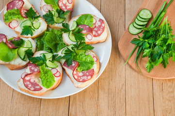 Sandwiches with sausage and greens on a white plate on a wooden table