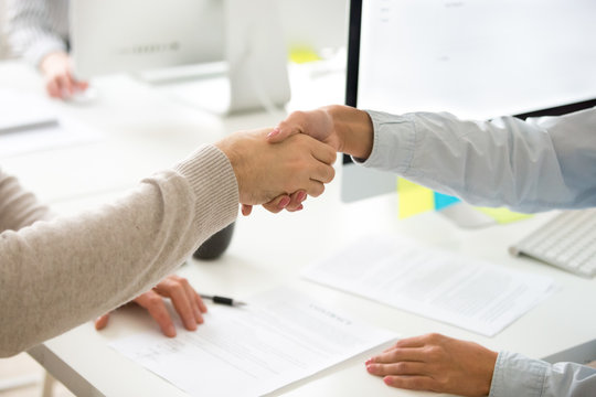 Handshake of man and woman after signing business contract, businessman and businesswoman shaking hands making employment agreement or hiring, buying insurance or becoming partners, close up view