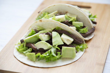 Mexican food. Carnitas street tacos in corn tortillas on wooden board. Side view.