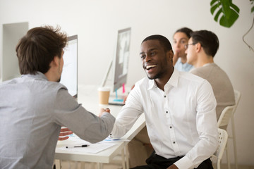 Obraz premium Friendly african advisor handshaking customer or colleague in office, smiling black and white entrepreneurs happy to make deal, excited diverse colleagues shake hands celebrating successful teamwork
