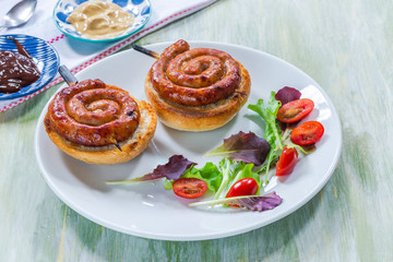 Chilli pork pinwheel sausages on a bun with fresh green leaf lettuce salad