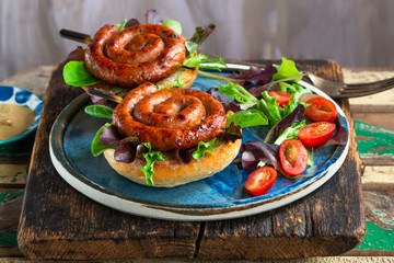 Chilli pork pinwheel sausages on a bun with fresh green leaf lettuce salad