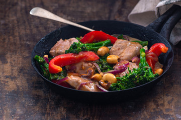 Sichuan pork, broccoli, red pepper and cashew stir-fry in a frying pan