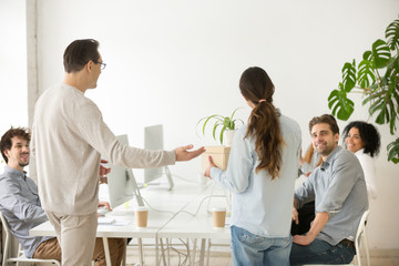 Company boss introducing new employee to colleagues, executive and friendly team welcoming greeting hired woman newcomer member holding box with belongings on first day at work in office, rear view