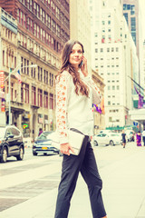 Young Eastern European Businesswoman traveling, working in New York, wearing white long sleeve shirt, black pants, holding leather purse, talking on cell phone, walking on street in Manhattan..