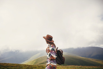 travel and wanderlust concept. traveler hipster girl in hat with backpack exploring misty sunny...
