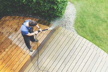 man cleaning terrace with a power washer - high water pressure cleaner on wooden terrace surface - 205575238