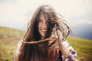 happy traveler hipster girl with windy hair and smiling, standing on top of sunny mountains. space...