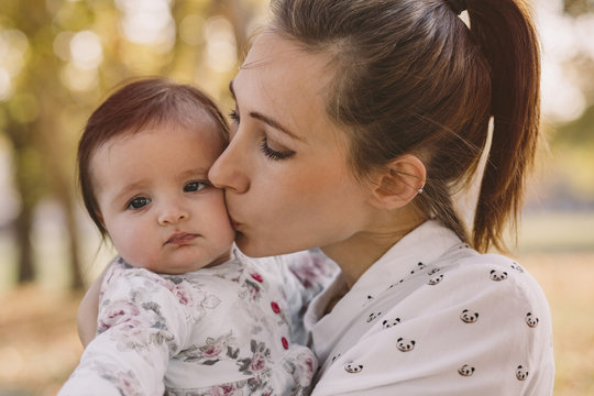 Close-up of mother kissing cute daughter at park during autumn