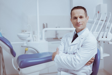 Fototapeta premium Your turn. Confident male dentist crossing hands while looking at camera