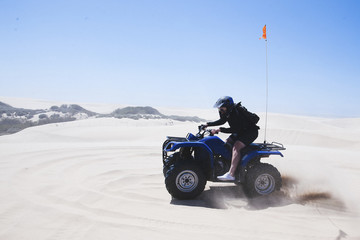 Full length of young man riding quadbike at Pismo Beach against clear sky during sunny day