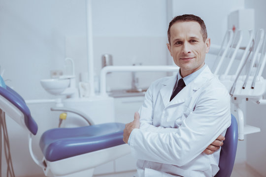 Your turn. Confident male dentist crossing hands while looking at camera