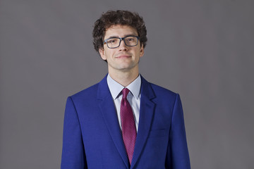 Intellectual boy with curly hair, glasses and blue jacket