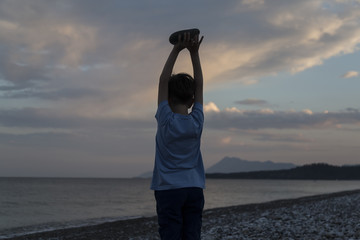 Fototapeta premium boy is holding the stone on the beach