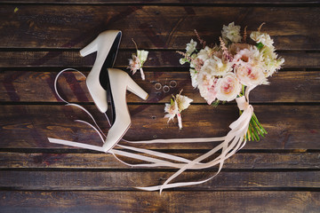 Bridal morning details composition. Top view of wedding rings, beautiful bouquet of pink flowers with ribbons, boutonniere and leather shoes. Flat lay.