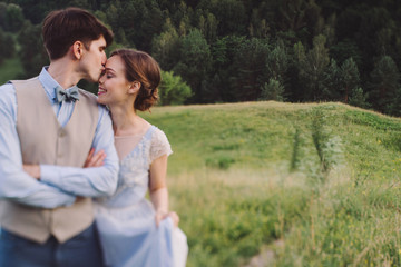 Romantic and happy caucasian couple in stylish clothes hugging on the background of beautiful nature. Love, relationships, romance, happiness concept. Man and woman walking outdoors together.