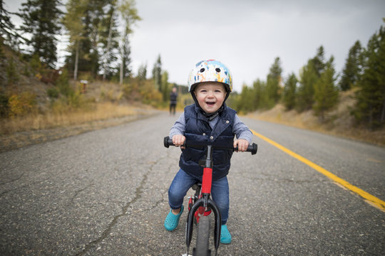Portrait of cute cheerful baby boy riding bicycle on country road