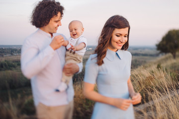 Young happy caucasian couple with little baby boy. Parents and son walking and having fun together. Mother and father playing with toddler outdoors. Family, parenthood, childhood, happiness concept.