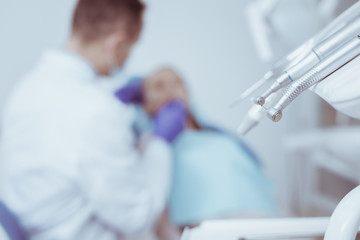 Dentists workplace. Selective focus of modern dental instruments while dentist diagnosing patient...